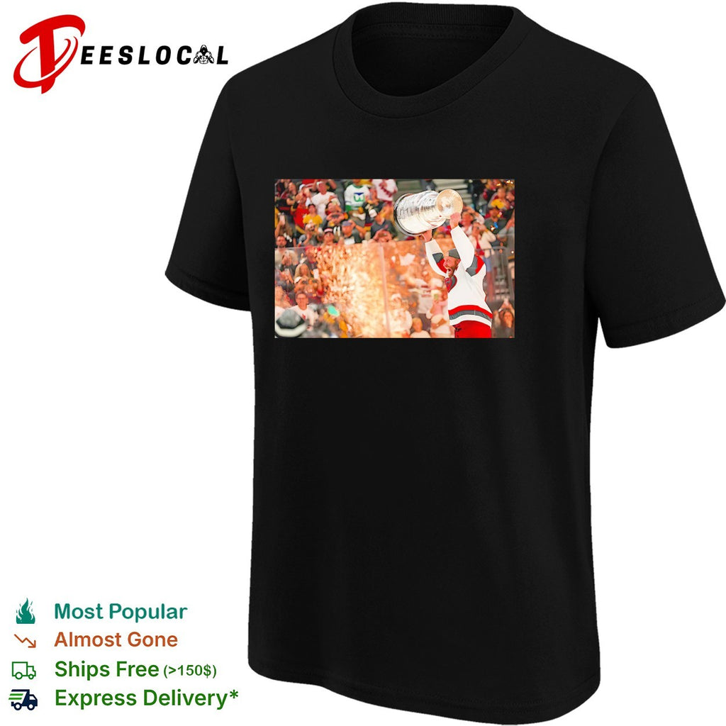 Carolina Hurricanes player hoisting Stanley Cup above head crowd fireworks triumphant moment shirt